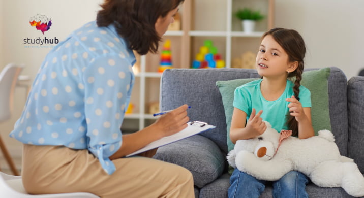 Young child sitting on a sofa talking with a professional during a one-on-one conversation in a comfortable indoor setting.