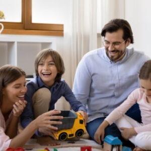 Happy parents playing with their children on the floor, demonstrating positive parenting skills and family bonding.