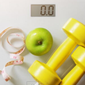 Digital weighing scale with an apple, measuring tape, and yellow dumbbells representing healthy weight management.