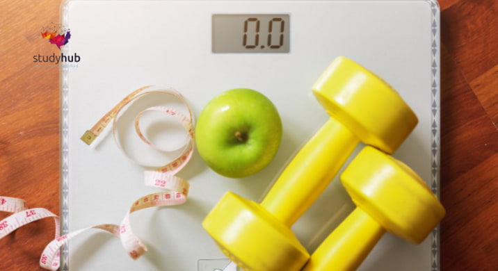 Digital weighing scale with an apple, measuring tape, and yellow dumbbells representing healthy weight management.