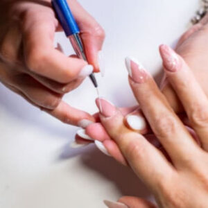 Nail technician applying acrylic nail enhancement to a client’s fingernail during a manicure session.