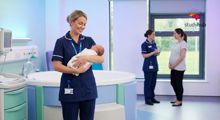 Nurse holding a newborn baby in a modern hospital maternity ward while colleagues consult with an expectant mother.