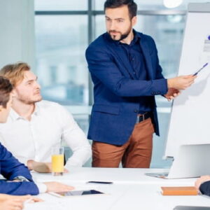 Business trainer presenting ideas to a professional team during a corporate meeting using a flip chart in a modern office.