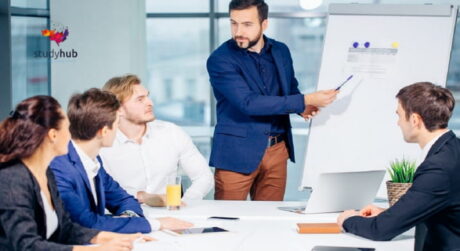 Business trainer presenting ideas to a professional team during a corporate meeting using a flip chart in a modern office.
