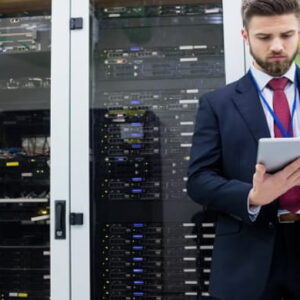 IT professional in a data center using a tablet while standing in front of server racks.