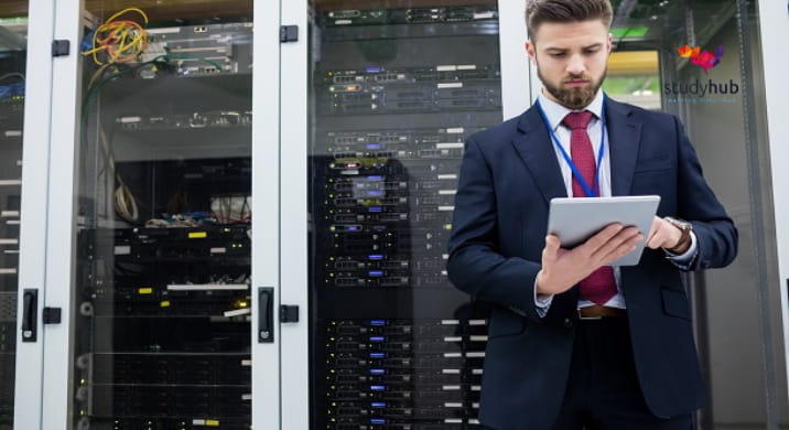 IT professional in a data center using a tablet while standing in front of server racks.