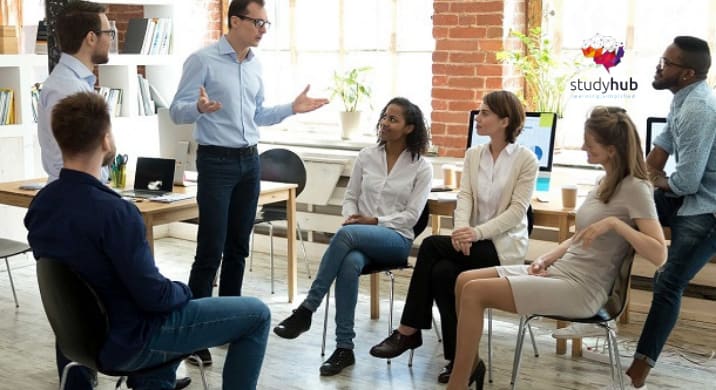 Team leader facilitating a group discussion with employees during a workplace training session in a modern office.
