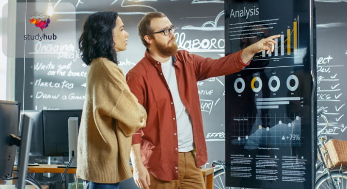 Two professionals analyzing business performance data on a digital dashboard with charts and graphs in a modern workspace.