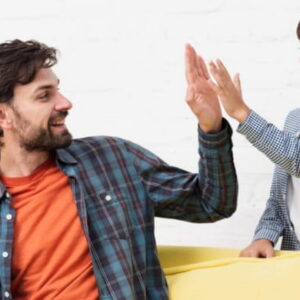 Father and son sitting on a couch giving each other a high five, showing positive bonding and encouragement at home.