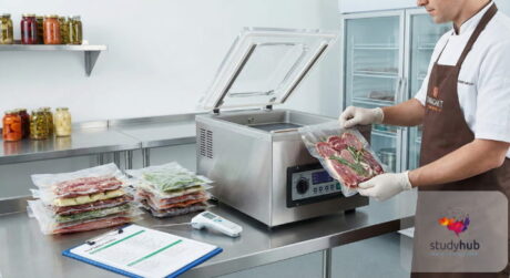 Professional food handler using a commercial vacuum packing machine to seal fresh ingredients in a kitchen.