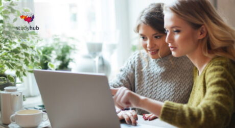 Two female students studying ethnobotany and herbal medicine on a laptop in a room with indoor plants.