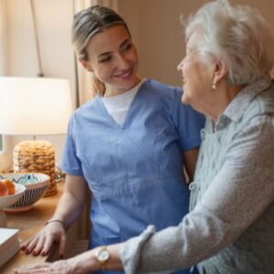 Caregiver assisting an elderly woman at home, providing compassionate support and companionship in a comfortable living space.