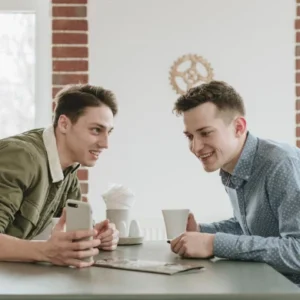 Two friends engaging in a lively conversation over coffee in a bright casual setting, representing the IsiXhosa: Everyday Conversation for Beginners course