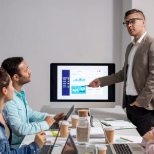 Technical lead presenting cloud application metrics to a team in a modern workspace, representing the Salesforce Heroku Masterclass