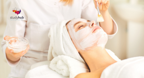 Woman receiving a facial treatment at a spa with a therapist applying a skincare mask using a brush.