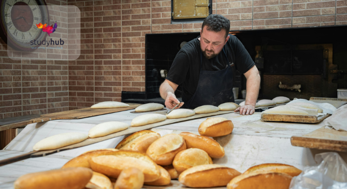 Baker preparing fresh bread dough in a bakery, shaping loaves on a floured work surface
