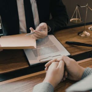 Lawyer handing over legal documents to a client across a desk with gavel and scales of justice