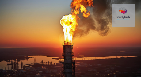 Gas flare tower burning excess gas at an oil refinery during sunset with industrial landscape in the background.