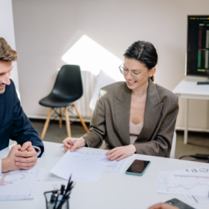Two business professionals analyzing financial charts and discussing investment strategy in a modern office setting